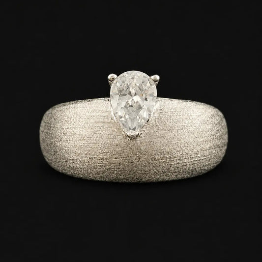 Pear cut diamond solitaire ring on model finger with wide textured silver band