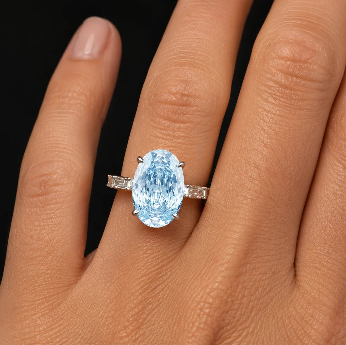 blue oval Rose cut engagement ring with baguette band worn on model finger
