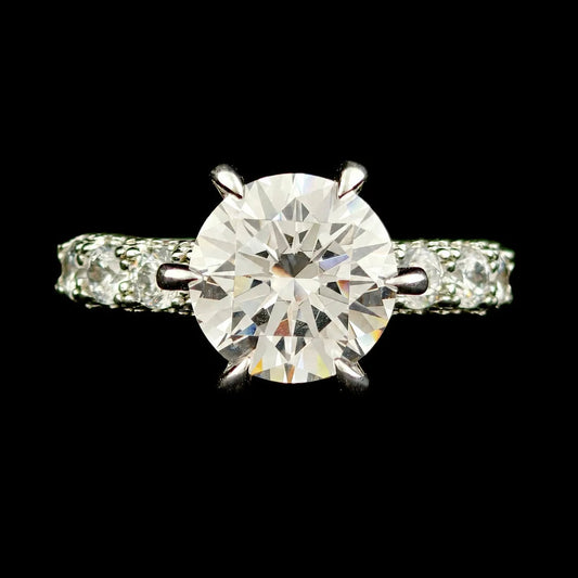 Top down view of round brilliant cut solitaire engagement ring in 6 prong setting with pave band